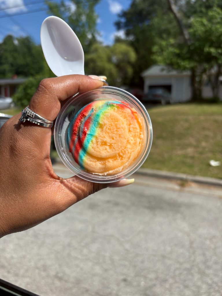 Hand holding a tropical rainbow LAB water ice cup